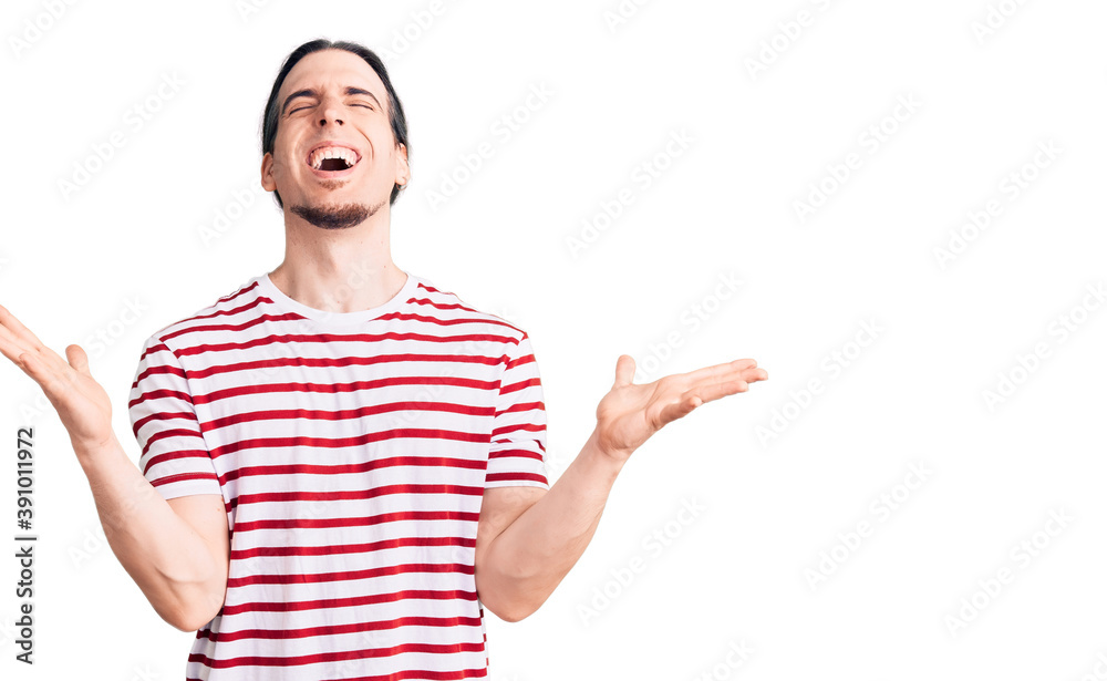 Young adult man with long hair wearing casual striped tshirt celebrating mad and crazy for success with arms raised and closed eyes screaming excited. winner concept Young adult man with long hair wearing casual striped tshirt celebrating mad and crazy for success with arms raised and closed eyes screaming excited. winner concept