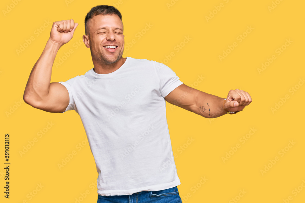 Naklejka premium Handsome muscle man wearing casual white tshirt dancing happy and cheerful, smiling moving casual and confident listening to music