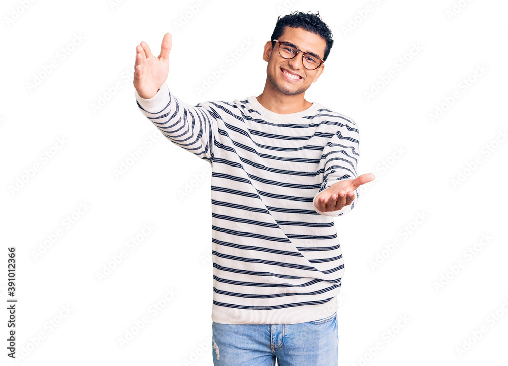 Hispanic handsome young man wearing casual clothes and glasses looking at the camera smiling with open arms for hug. cheerful expression embracing happiness. Hispanic handsome young man wearing casual clothes and glasses looking at the camera smiling with open arms for hug. cheerful expression embracing happiness.