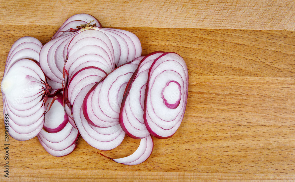 A juicy onion cut into rings on a wooden board.