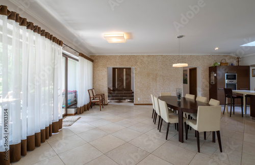 Modern interior of spacious kitchen in luxury private house. Wooden table and chairs. Panorama windows.