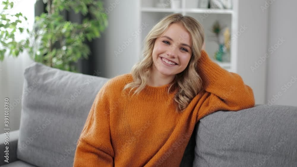Portrait of smiling young woman with blond hair dressed in knitted yellow sweater sitting on couch. Concept female beauty and happiness. Portrait of smiling young woman with blond hair dressed in knitted yellow sweater sitting on couch. Concept female beauty and happiness.