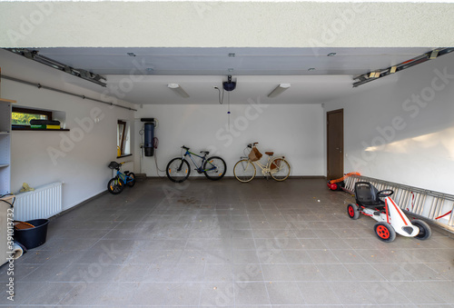 Fototapeta Bicycles and children's cars in the garage with tiled floor
