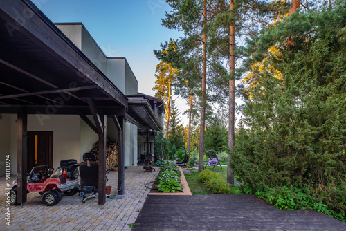 View of green garden of luxury private cottage near a pine forest. Exterior of modern private house. Swing in the garden.