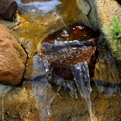 Kaskada wodna zbudowana z naturalnych kamieni i skał w przydomowym ogrodzie 