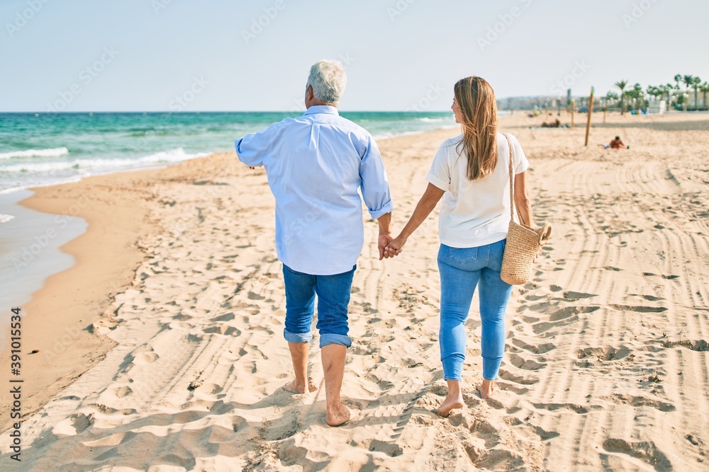 Middle age hispanic couple walking at the beach on back view. Middle age hispanic couple walking at the beach on back view.