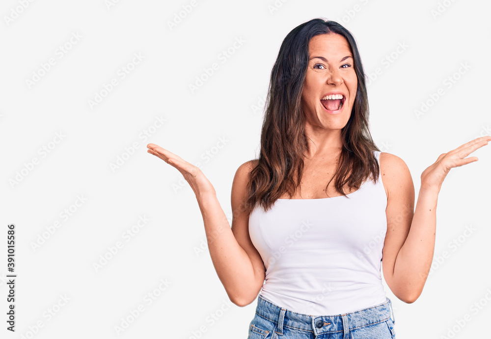 Young beautiful brunette woman wearing casual sleeveless t-shirt celebrating crazy and amazed for success with arms raised and open eyes screaming excited. winner concept Young beautiful brunette woman wearing casual sleeveless t-shirt celebrating crazy and amazed for success with arms raised and open eyes screaming excited. winner concept
