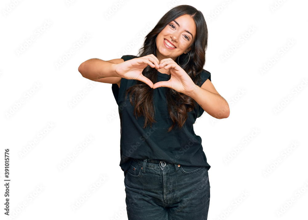 Beautiful brunette young woman wearing black shirt smiling in love doing heart symbol shape with hands. romantic concept. Beautiful brunette young woman wearing black shirt smiling in love doing heart symbol shape with hands. romantic concept.