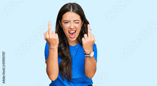 Beautiful brunette young woman wearing casual clothes showing middle finger doing fuck you bad expression, provocation and rude attitude. screaming excited