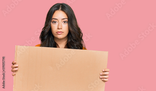 Fotografie Beautiful brunette young woman holding cardboard blank empty banner thinking att