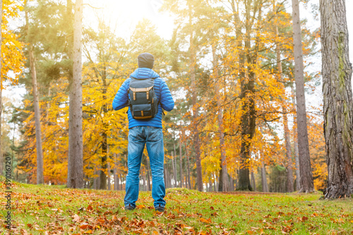 Man standing in the forest with orange autumn trees and leaves - Young man alone in a remote wood, isolating and escaping from city and busy life - lifestyle and nature © william87