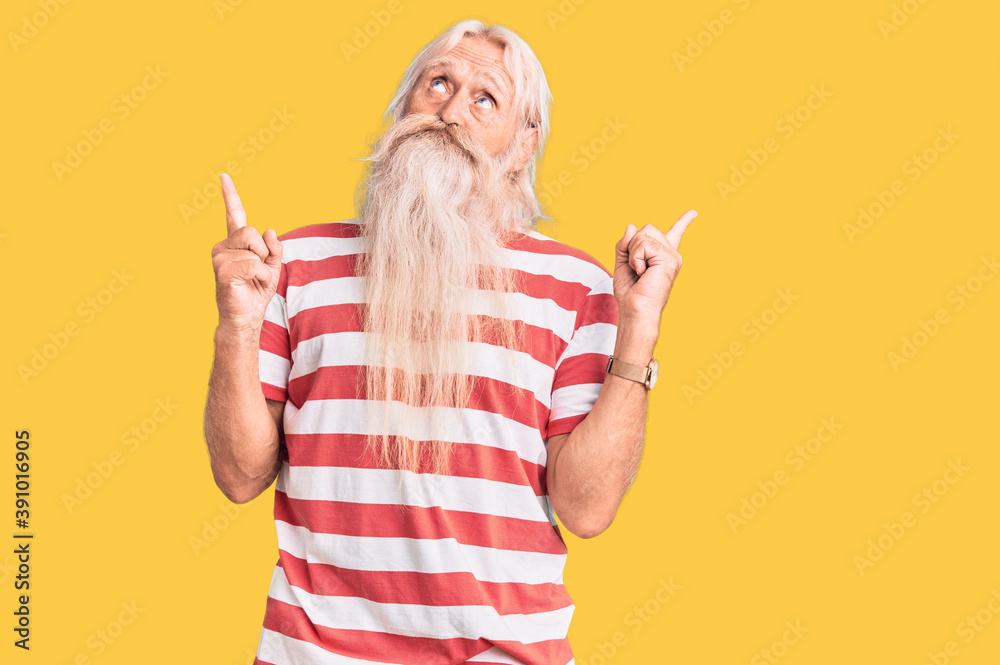 Old senior man with grey hair and long beard wearing striped tshirt pointing up looking sad and upset, indicating direction with fingers, unhappy and depressed. Old senior man with grey hair and long beard wearing striped tshirt pointing up looking sad and upset, indicating direction with fingers, unhappy and depressed.