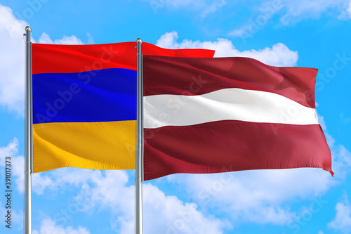 Latvia and Armenia national flag waving in the windy deep blue sky. Diplomacy and international relations concept.
