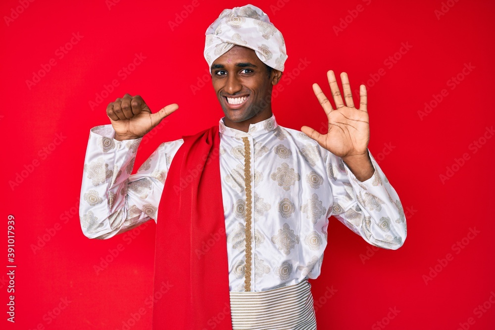 Handsome indian man wearing tradition sherwani saree clothes showing and pointing up with fingers number six while smiling confident and happy. Handsome indian man wearing tradition sherwani saree clothes showing and pointing up with fingers number six while smiling confident and happy.