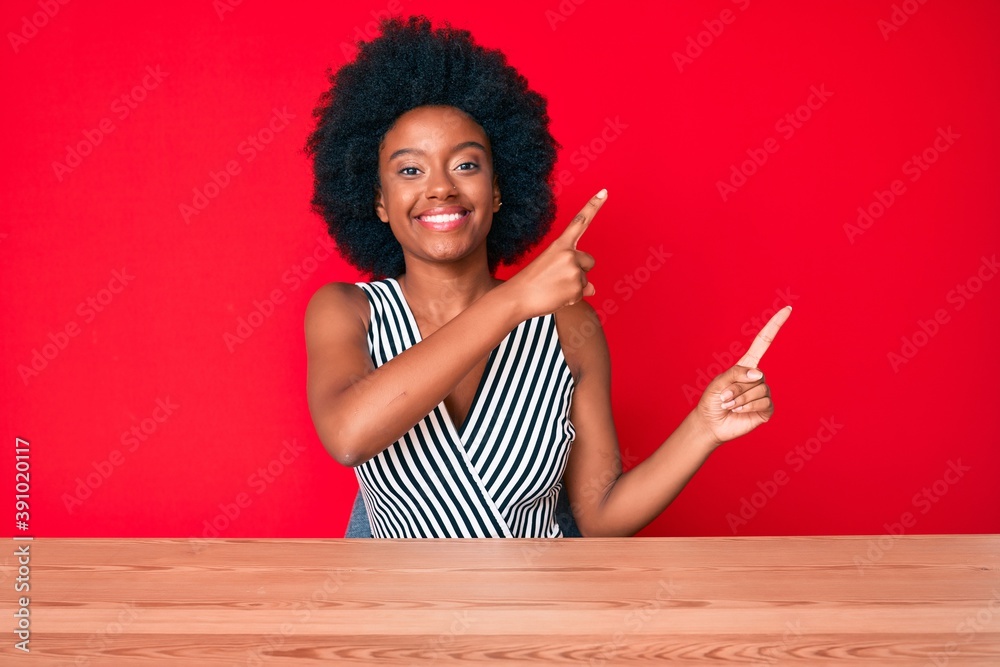 Young african american woman wearing casual clothes smiling and looking at the camera pointing with two hands and fingers to the side. Young african american woman wearing casual clothes smiling and looking at the camera pointing with two hands and fingers to the side.