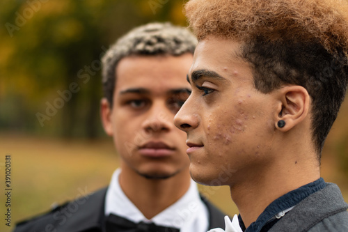 Profile portrait of handsome young gay man of color with his boyfriend blurred in the background. Concept of same sex love, equality and LGBT rights. Black lives matter! © arrideo
