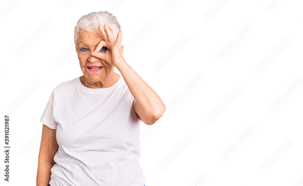 Senior beautiful woman with blue eyes and grey hair wearing casual white tshirt doing ok gesture with hand smiling, eye looking through fingers with happy face. Senior beautiful woman with blue eyes and grey hair wearing casual white tshirt doing ok gesture with hand smiling, eye looking through fingers with happy face.
