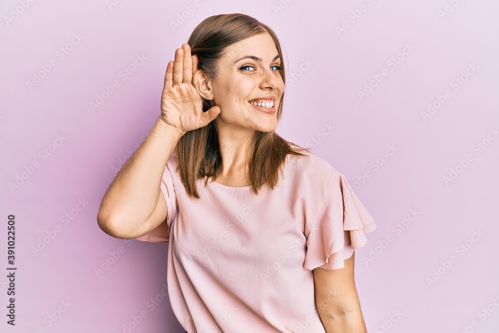 Beautiful caucasian woman wearing casual clothes smiling with hand over ear listening and hearing to rumor or gossip. deafness concept. Beautiful caucasian woman wearing casual clothes smiling with hand over ear listening and hearing to rumor or gossip. deafness concept.