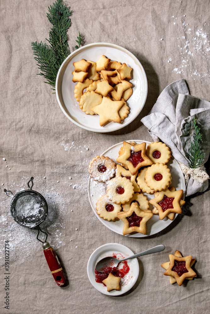 Homemade traditional Linz shortbread biscuits cookies with red jam and icing sugar on ceramic plate over linen tablecloth. Homemade traditional Linz shortbread biscuits cookies with red jam and icing sugar on ceramic plate over linen tablecloth.