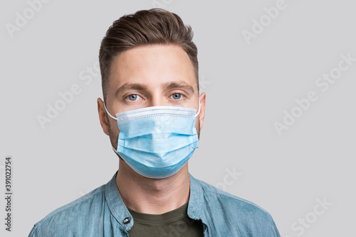 Portrait of a young man wearing protective face mask, Masked men studio portrait isolated on gray background, Social distancing, pandemic, corona virus protection, healthy lifestyle, people concept