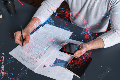 Double exposure of man signing contract with phone and world map network hologram. Concept of international business.
