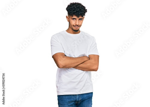 Young arab man wearing casual white t shirt skeptic and nervous, disapproving expression on face with crossed arms. negative person.