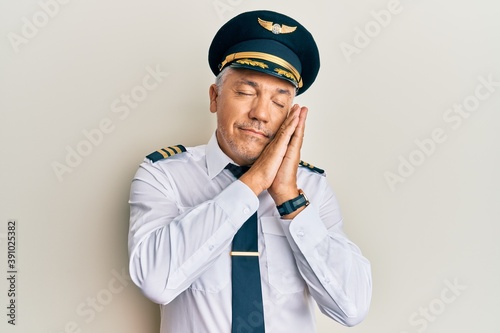 Wallpaper Mural Handsome middle age mature man wearing airplane pilot uniform sleeping tired dreaming and posing with hands together while smiling with closed eyes