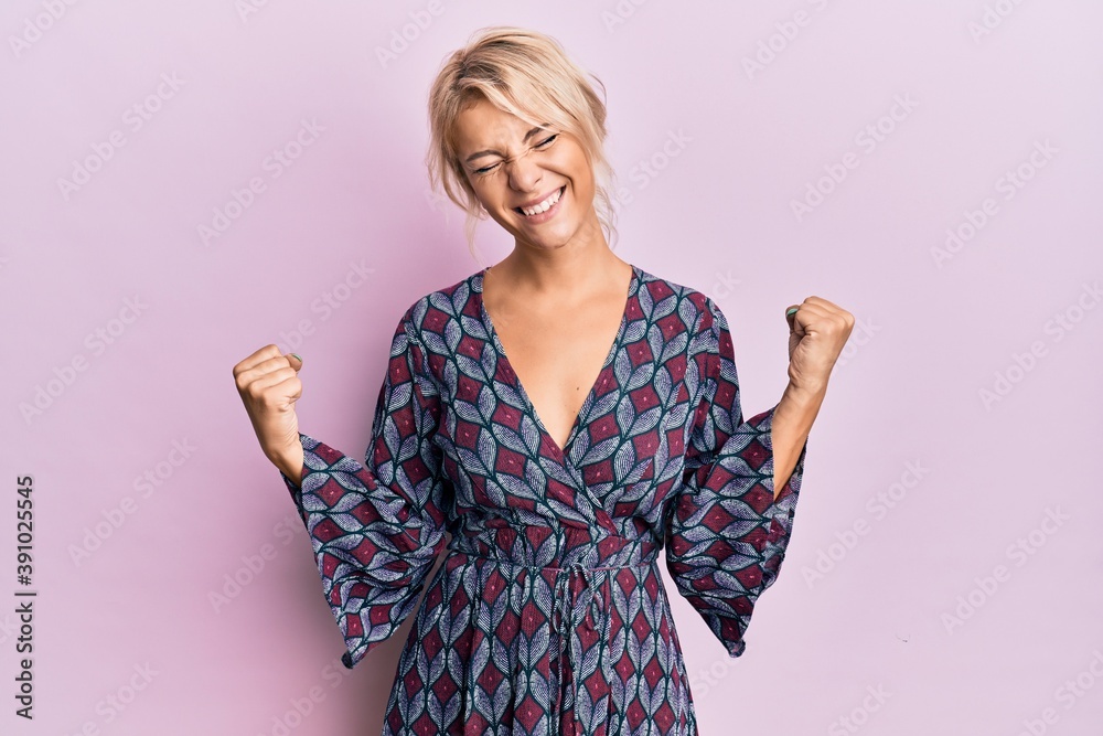 Young blonde girl wearing casual clothes very happy and excited doing winner gesture with arms raised, smiling and screaming for success. celebration concept. Young blonde girl wearing casual clothes very happy and excited doing winner gesture with arms raised, smiling and screaming for success. celebration concept.