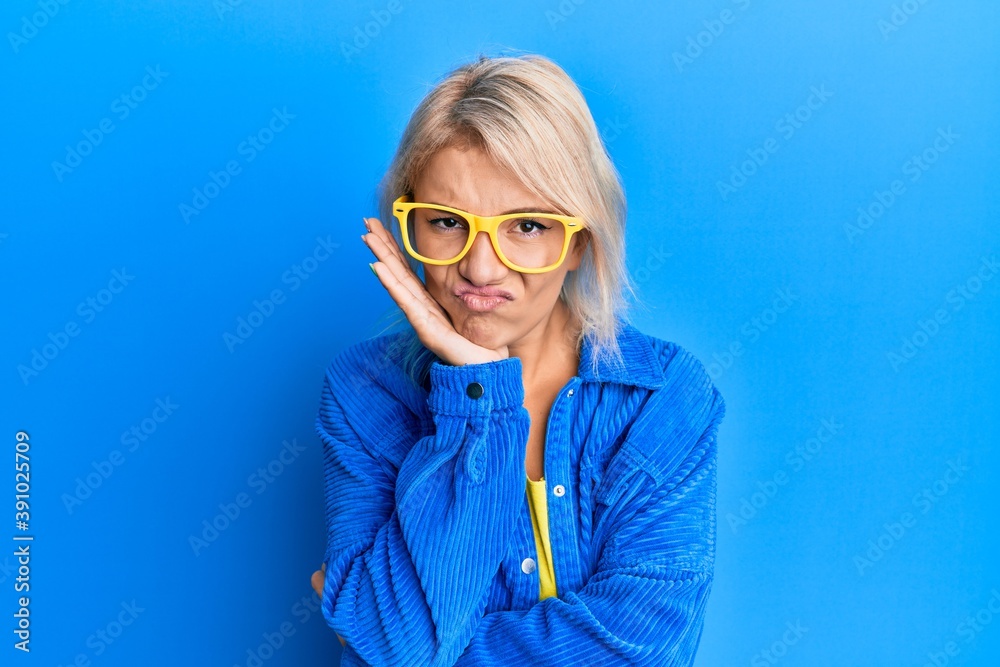 Young blonde girl wearing casual clothes and glasses thinking looking tired and bored with depression problems with crossed arms. Young blonde girl wearing casual clothes and glasses thinking looking tired and bored with depression problems with crossed arms.