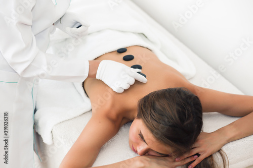 Young woman with stones on her back in spa salon