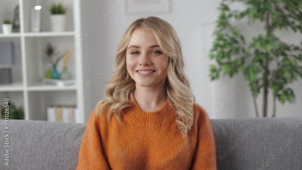 Charming blonde female posing on camera while relaxing on cozy sofa at bright living room. Lazy weekend at home. Smiling young woman. Charming blonde female posing on camera while relaxing on cozy sofa at bright living room. Lazy weekend at home. Smiling young woman.