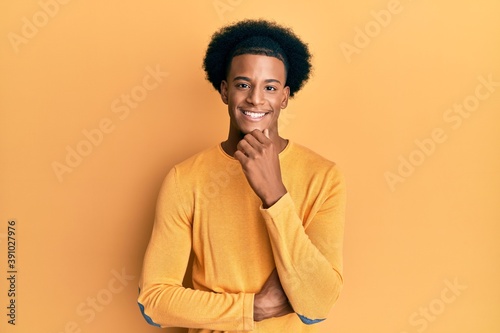 African american man with afro hair wearing casual clothes smiling looking confident at the camera with crossed arms and hand on chin. thinking positive.