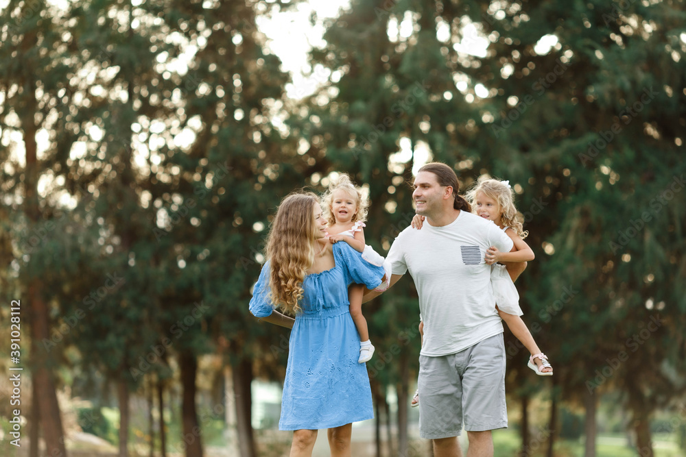 Parents Giving Children Piggybacks In Countryside, enjoing time together. Happy family concept. Blurred trees background. Parents Giving Children Piggybacks In Countryside, enjoing time together. Happy family concept. Blurred trees background.