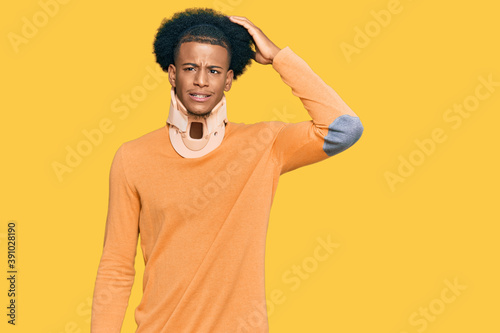 African american man with afro hair wearing cervical neck collar confuse and wonder about question. uncertain with doubt, thinking with hand on head. pensive concept.