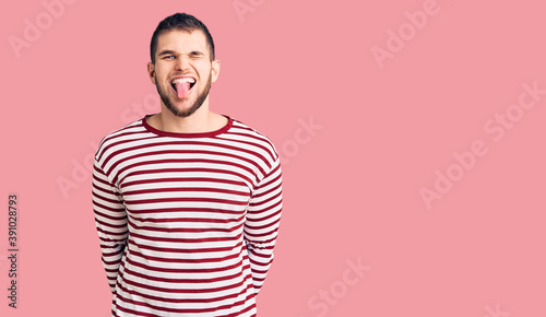 Wallpaper Mural Young handsome man wearing striped sweater sticking tongue out happy with funny expression. emotion concept. Torontodigital.ca