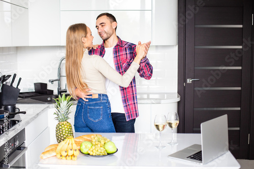 Happy young couple dancing in kitchen at home