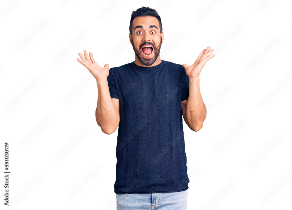 Fototapeta premium Young hispanic man wearing casual clothes celebrating victory with happy smile and winner expression with raised hands
