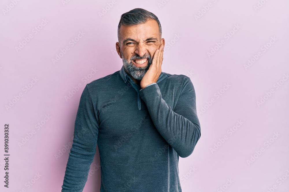 Middle age handsome man wearing casual clothes touching mouth with hand with painful expression because of toothache or dental illness on teeth. dentist Middle age handsome man wearing casual clothes touching mouth with hand with painful expression because of toothache or dental illness on teeth. dentist