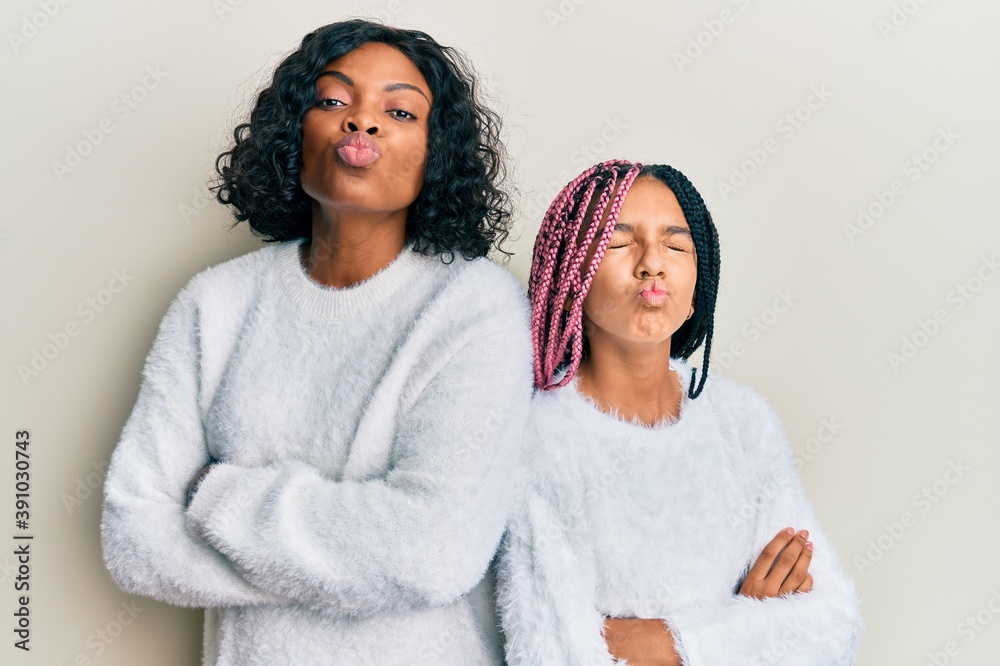 Beautiful african american mother and daughter with arms crossed gesture looking at the camera blowing a kiss being lovely and sexy. love expression. Beautiful african american mother and daughter with arms crossed gesture looking at the camera blowing a kiss being lovely and sexy. love expression.