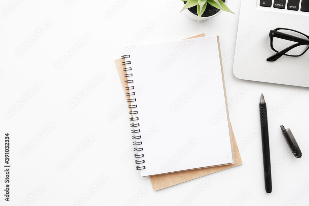 Blank notebook with pen are on top of white office desk table with laptop computer and supplies. Top view with copy space, flat lay. Blank notebook with pen are on top of white office desk table with laptop computer and supplies. Top view with copy space, flat lay.
