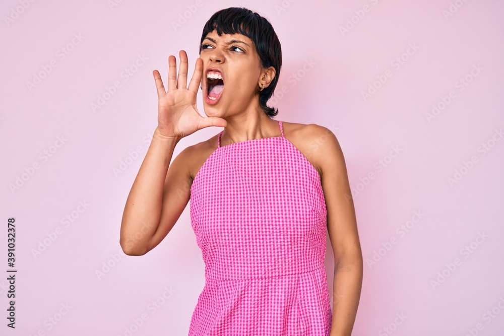 Beautiful brunettte woman wearing casual clothes over pink background shouting and screaming loud to side with hand on mouth. communication concept. Beautiful brunettte woman wearing casual clothes over pink background shouting and screaming loud to side with hand on mouth. communication concept.