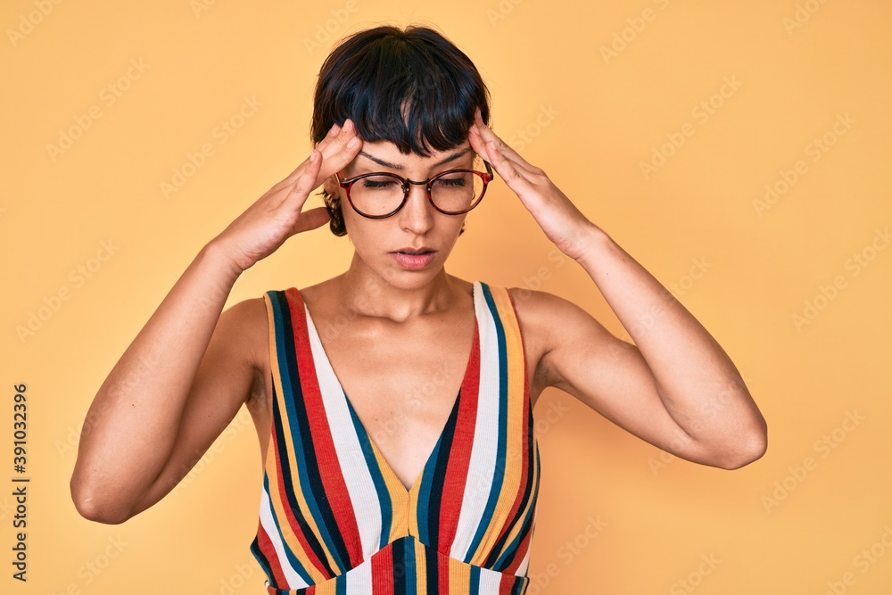 Beautiful brunettte woman wearing casual clothes and glasses suffering from headache desperate and stressed because pain and migraine. hands on head. Beautiful brunettte woman wearing casual clothes and glasses suffering from headache desperate and stressed because pain and migraine. hands on head.