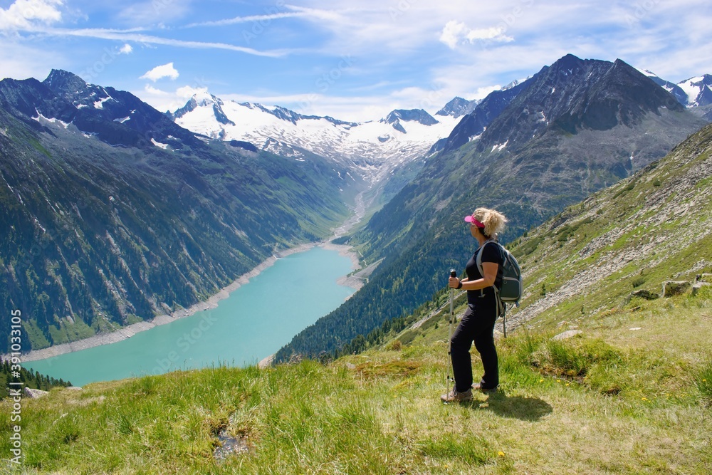 Woman hiker watching beautiful summer mountain scenery in  Zillertal area, Austrian Alps. Schlegeisspeicher reservoir view.