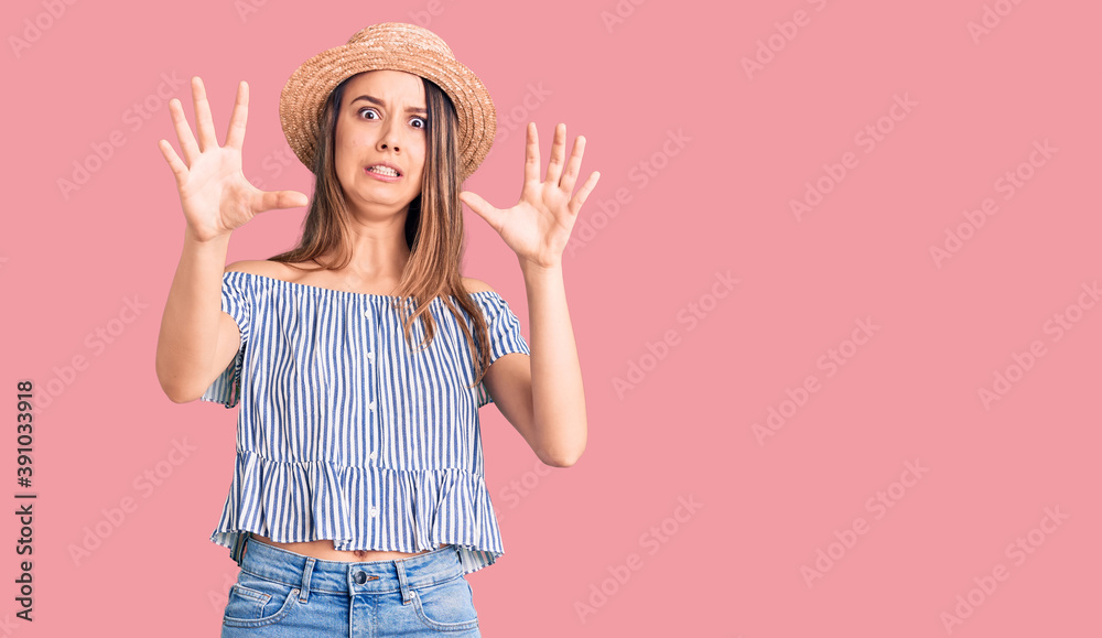 Young beautiful girl wearing hat and t shirt afraid and terrified with fear expression stop gesture with hands, shouting in shock. panic concept. Young beautiful girl wearing hat and t shirt afraid and terrified with fear expression stop gesture with hands, shouting in shock. panic concept.