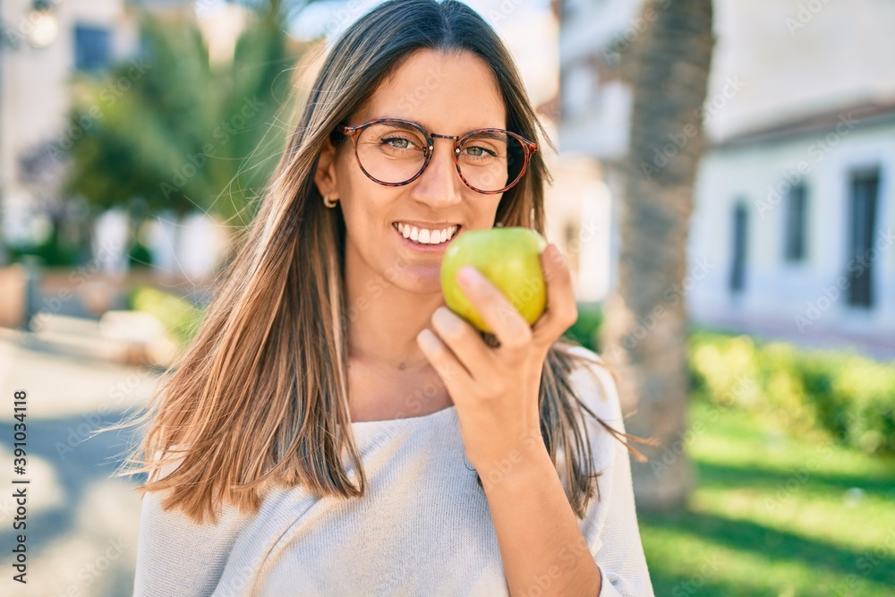 Young caucasian woman smiling happy eating green apple at the city. Young caucasian woman smiling happy eating green apple at the city.