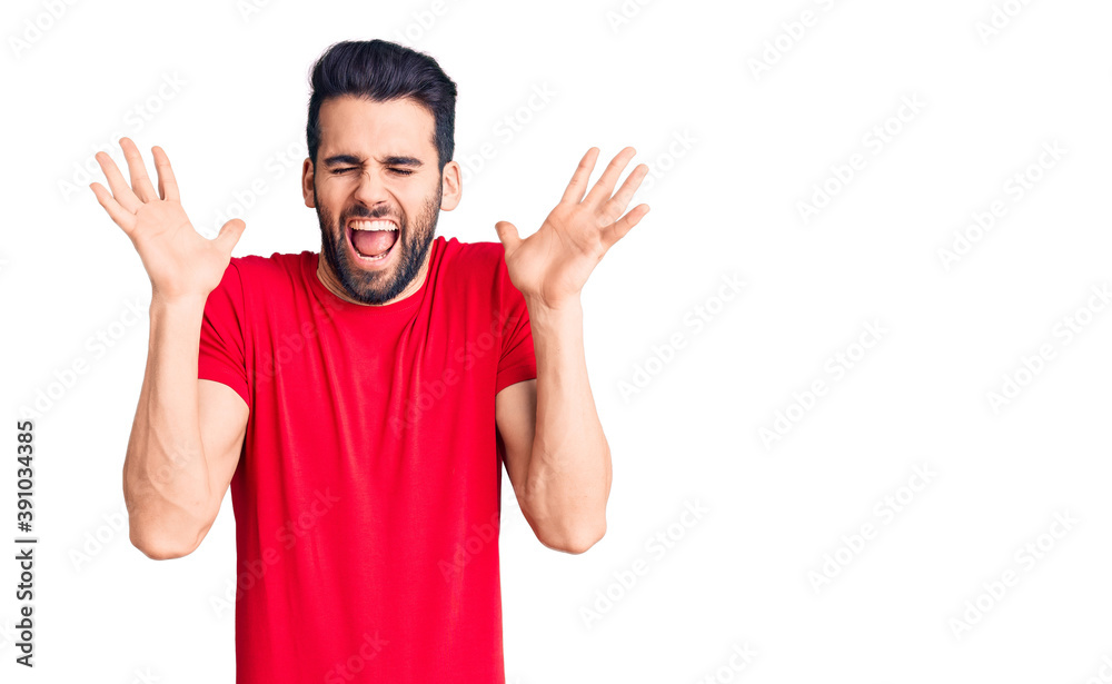 Young handsome man with beard wearing casual t-shirt celebrating mad and crazy for success with arms raised and closed eyes screaming excited. winner concept Young handsome man with beard wearing casual t-shirt celebrating mad and crazy for success with arms raised and closed eyes screaming excited. winner concept