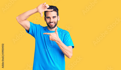 Young handsome man with beard wearing casual t-shirt smiling making frame with hands and fingers with happy face. creativity and photography concept.