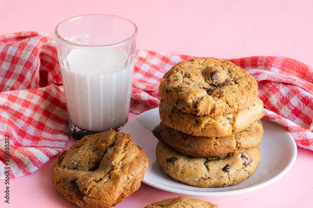 Stack of chocolate chip cookies beside a glass of milk in front of a pink background Stack of chocolate chip cookies beside a glass of milk in front of a pink background