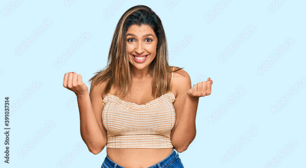 Beautiful brunette woman wearing casual clothes celebrating surprised and amazed for success with arms raised and open eyes. winner concept. Beautiful brunette woman wearing casual clothes celebrating surprised and amazed for success with arms raised and open eyes. winner concept.