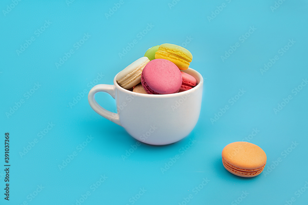 French multicolored macaroons in a white teacup. Dessert. French multicolored macaroons in a white teacup. Dessert.